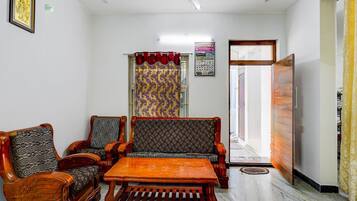 A room with a ceiling fan, patterned curtains, a wooden sofa, and a coffee table.