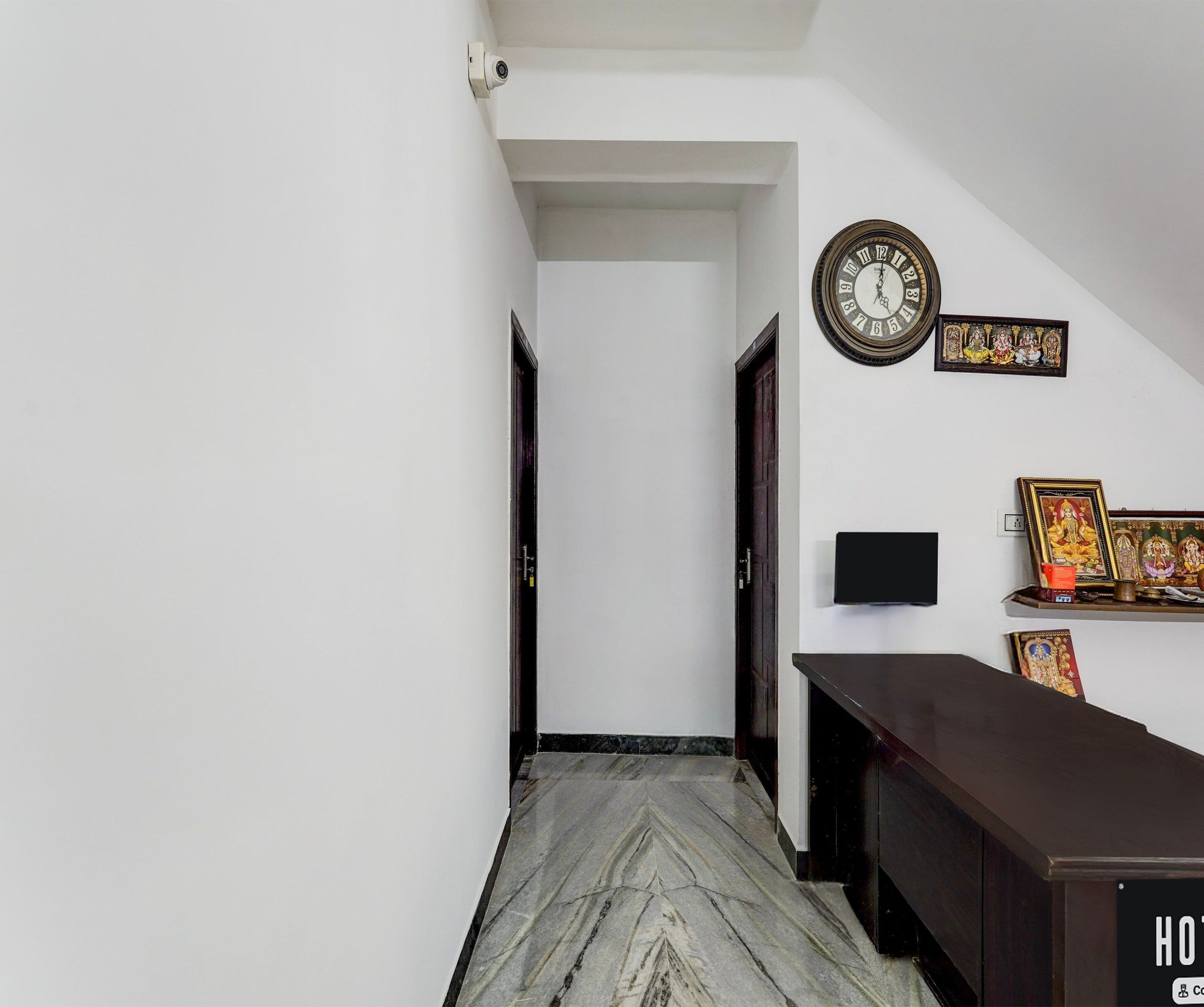 A hallway with a marble floor, a clock, and religious wall art.
