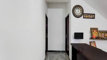 A hallway with a marble floor, a clock, and religious wall art.