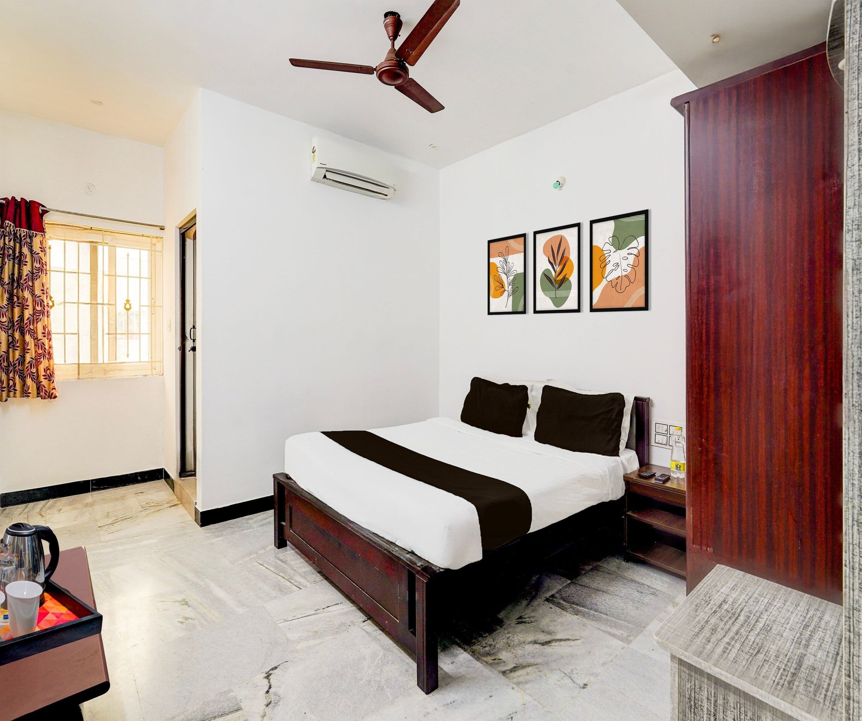 A hotel room with a bed, a nightstand, a water bottle, and a ceiling fan.