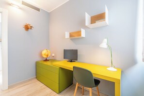 A modern office space with a yellow desk, a green chair, a globe, a computer monitor, and a desk lamp. - VerdeBlù - Home Design by the Sea (Arma di Taggia)