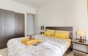 Ein Hotelzimmer mit Bett, Schrank, Nachttisch und Lampe.