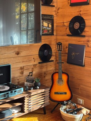 A room with wooden walls, a guitar, a turntable, and various records. - TheHiddenPond|Sauna|Hottub| Stargazing|Fishing|Ski (Windham)