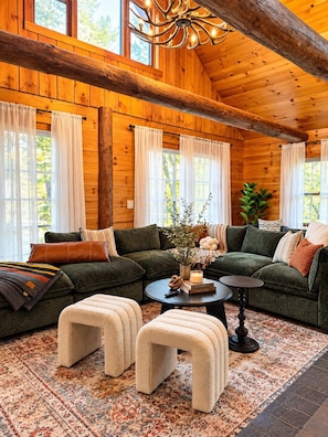A cozy log cabin interior with a sectional sofa, a coffee table, and a fireplace. - TheHiddenPond|Sauna|Hottub| Stargazing|Fishing|Ski (Windham)