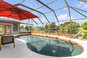 A swimming pool with a covered area, a red umbrella, and a view of a lake. - Private Pool + Bar - Pet Friendly - Sleeps 6 (Port Orange)