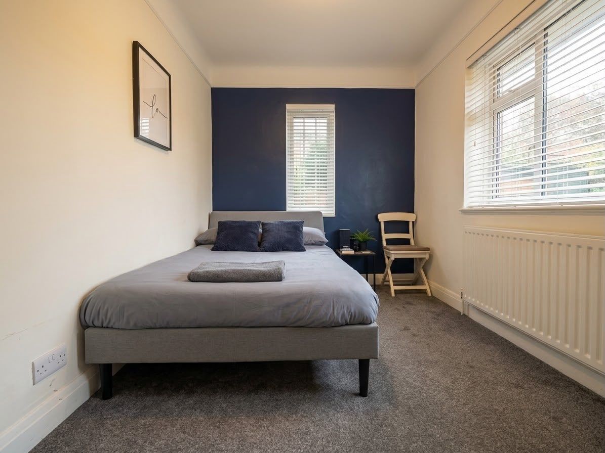 Une chambre à coucher avec un lit, une chaise, une fenêtre et un radiateur.