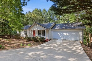 A single-story house with a front porch, a garage, and a driveway leading to the entrance. - 3 B/2.5 BA, Pets OK, Fenced Backyard, Longer Stays OK, AT&T's fastest Wi-Fi (Gainesville)