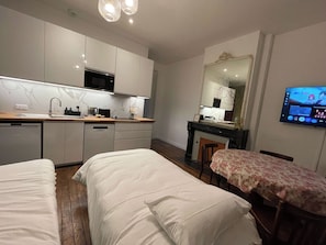 Habitación de hotel pequeña con kitchenette, cama, una mesita y televisor.