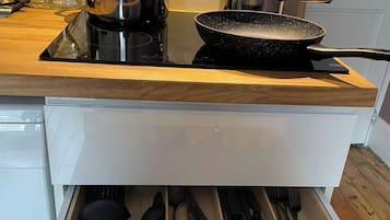 Une cuisine équipée d’une cuisinière, de casseroles et d’un tiroir contenant des ustensiles de cuisine.