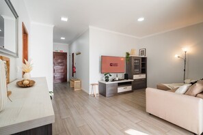 Ein modernes Wohnzimmer mit einer Couch, einem Fernseher, einem Schrank und Holzboden.