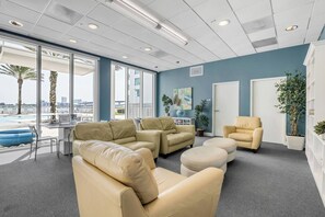 Ein stilvoller Lounge-Bereich mit Ledersofas, einem Couchtisch und Blick auf Pool und Stadtlandschaft durch große Fenster.