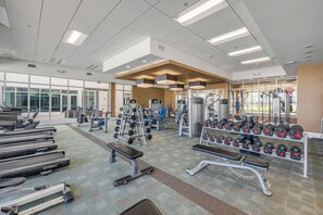 Une salle de sport équipée de machines de cardio, de machines de musculation et d’haltères.