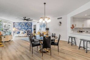 Ein modernes Wohnzimmer mit Essbereich, einer Küche und einem Deckenventilator.
