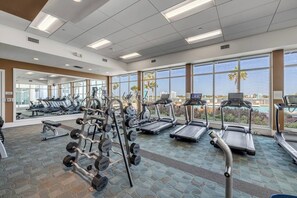 A gym with treadmills, weight machines, and dumbbells. - 20th Floor Luxury Condo | Halifax River Views (Holly Hill)
