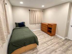 A bedroom with a bed, a dresser, a window with curtains, and a door. - Spacious 4BR Retreat - Game Room, Full Kitchen, Private workspace & Four Seasons (Rockford)