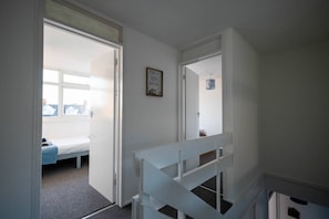 A hallway with a bed and a door leading to another room. - 3-bed flat by Felixstowe seafront with roof terrace and parking (Felixstowe)