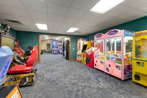 A row of arcade games in a room with a carpeted floor and a door leading to another area. - 1BR Blue Ridge Resort Condo · Indoor Pool, Hot Tub & Tennis · Sapphire NC (Sapphire)