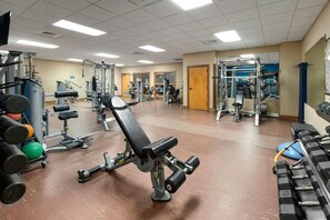 Une salle de sport équipée de divers appareils d’entraînement, notamment des machines à poids et des poids libres.