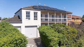 Ein zweistöckiges Haus mit Garage, Solaranlage auf dem Dach und einem gepflegten Garten.