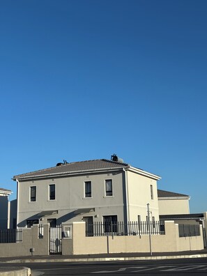 A two-story building with a flat roof, a gated entrance, and a clear sky. - Luxury Feel, Mountain Views and Comfort at The Town House (Cape Town)