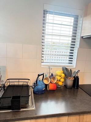 A kitchen with a window, a kettle, pots, and utensils on the counter. - Luxury Feel, Mountain Views and Comfort at The Town House (Cape Town)