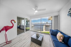 Een moderne woonkamer met een balkon, een rode flamingo-beeldje en een uitzicht op de stadshemel.