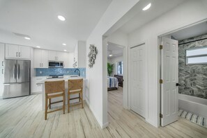 A modern kitchen with white cabinets, a stainless steel refrigerator, and a blue backsplash. - 2-bedroom 2- bath Waterfront Paradise With Intracoastal Views & Dock (West Palm Beach)
