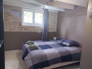 Ein Schlafzimmer mit einem Bett, einem Fenster und einer Steinwand.