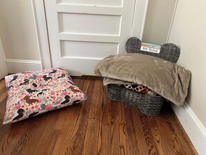 A corner of a room with a wooden floor, a pet bed with a label, and a cushion with a floral pattern. - *Charming* 3bd dog-friendly entire Home close to DT (Winston-Salem)