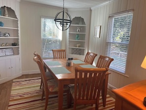 A dining area with a wooden table, chairs, a chandelier, and a striped rug. - *Charming* 3bd dog-friendly entire Home close to DT (Winston-Salem)