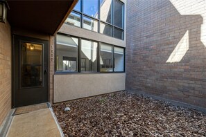 A building with a brick exterior, large windows, and a wooden deck area. - Remodeled 1BR · 5-Min Walk to Ski · Pool, Hot Tub, Sauna & Golf Views (Park City)