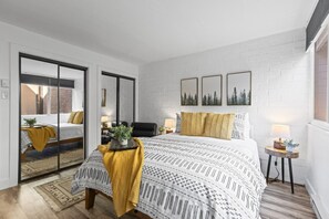 A modern bedroom with a bed, bedside tables, a mirror, and a view through a sliding door. - Remodeled 1BR · 5-Min Walk to Ski · Pool, Hot Tub, Sauna & Golf Views (Park City)