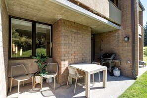 An outdoor patio with a table and chairs, a grill, and a potted plant. - Remodeled 1BR · 5-Min Walk to Ski · Pool, Hot Tub, Sauna & Golf Views (Park City)