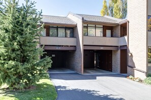 A modern two-story building with a garage entrance, a brick facade, and a well-maintained lawn. - Remodeled 1BR · 5-Min Walk to Ski · Pool, Hot Tub, Sauna & Golf Views (Park City)