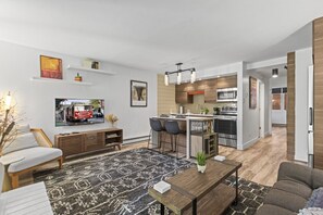 A modern living room with a sofa, a coffee table, and a TV. - Remodeled 1BR · 5-Min Walk to Ski · Pool, Hot Tub, Sauna & Golf Views (Park City)