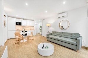 A modern living room with a grey sofa, a round coffee table, and a dining area with a white table and chairs. - La Carihuela Seafront (Torremolinos)