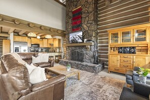 A spacious living area with a stone fireplace, leather sofa, and wooden cabinets. - Private Hot Tub · Sleeps 10 · Under a 5-Minute Walk to Silver Star Lift (Park City)