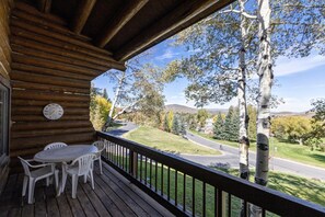 A wooden deck with a table and chairs, overlooking a road and trees. - Private Hot Tub · Sleeps 10 · Under a 5-Minute Walk to Silver Star Lift (Park City)