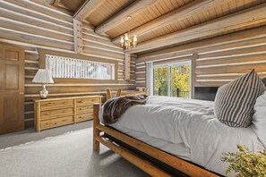 Quarto de cabana de madeira com cama, cômoda e janela.