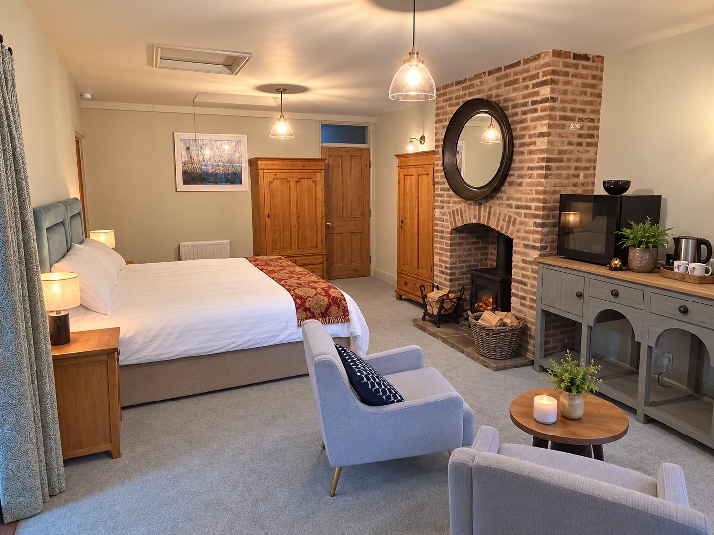 A bedroom with a bed, a fireplace, a television, and a seating area.