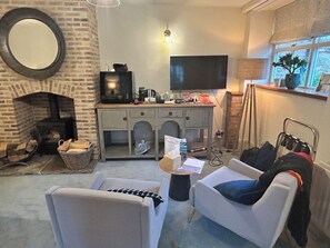 Una sala de estar acogedora con chimenea, televisor, escritorio y una zona de estar confortable.