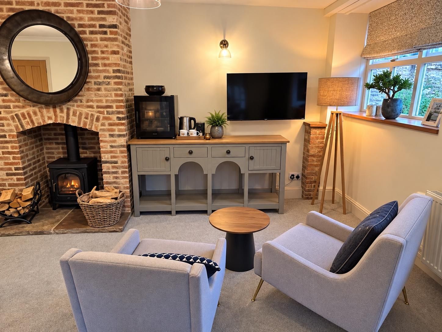 A cozy living room with a fireplace, comfortable seating, a flat-screen TV, and a window with a view.