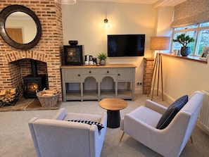 Un salon chaleureux avec une cheminée, des fauteuils confortables, un téléviseur à écran plat et une fenêtre offrant une belle vue.