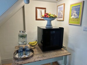 A wooden table with a fruit bowl, a jar, and a banana.