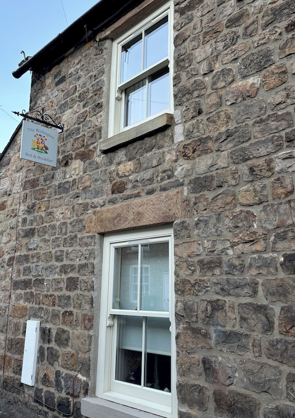 A stone building with a sign indicating it offers bed and breakfast services.