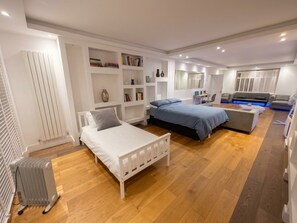 A modern bedroom with two beds, a desk, a sofa, and built-in shelving. - Peaceful bedroom house in welcoming London neighborhood (London)