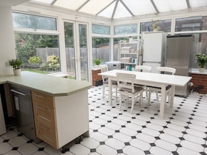 A conservatory with a dining area, a built-in kitchen, and a view of the garden. - Peaceful bedroom house in welcoming London neighborhood (London)