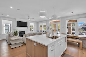 A modern kitchen with a central island, built-in appliances, and a large window providing natural light. - Luxury 5BR | Sleeps 16 | 1 Block to Beach & Boardwalk (Ocean City)