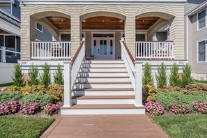 A two-story house with a front porch, wooden steps, and a white railing. - Luxury 5BR | Sleeps 16 | 1 Block to Beach & Boardwalk (Ocean City)
