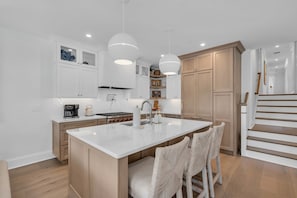 A modern kitchen with white cabinetry, a central island, and pendant lighting. - Luxury 5BR | Sleeps 16 | 1 Block to Beach & Boardwalk (Ocean City)